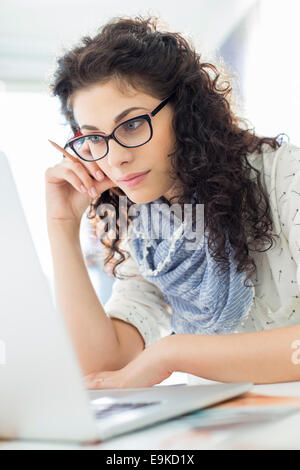 Businesswoman using laptop at desk in creative office Stock Photo