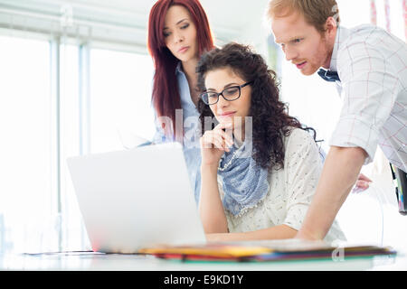 Creative business colleagues using laptop at desk in office Stock Photo