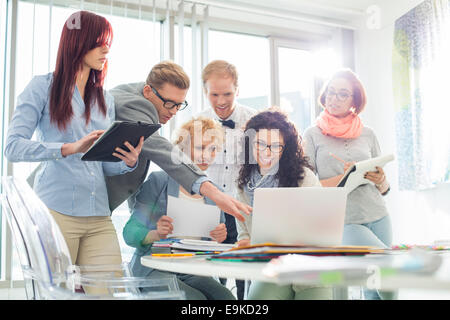 Smiling creative businesspeople working on laptop at desk in office Stock Photo