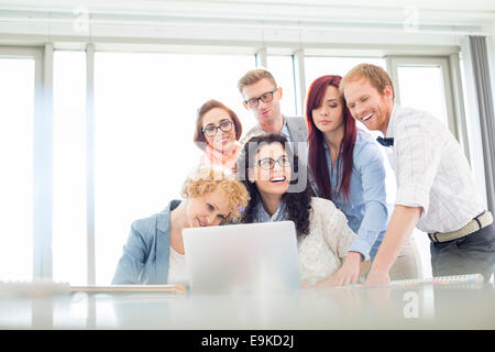 Happy business colleagues with laptop discussing in creative office Stock Photo
