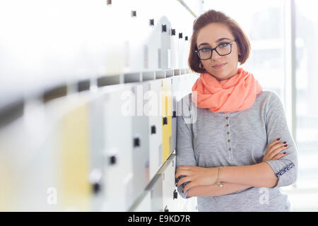 Portrait of confident businesswoman standing arms crossed in locker room at creative office Stock Photo