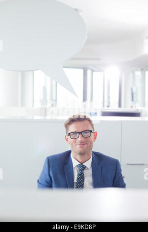 Portrait of confident businessman with speech bubble in office Stock Photo