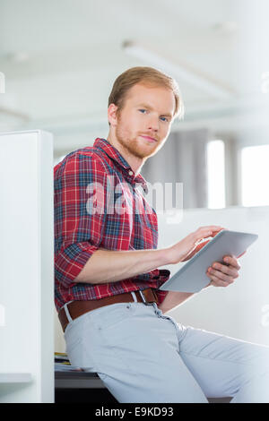 Portrait of confident businessman using tablet PC in creative office Stock Photo