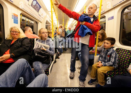 Families with children travelling in a carriage on a London Underground tube train, London UK Stock Photo