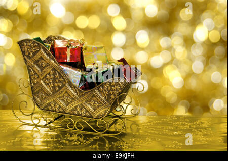 Christmas sleigh or sled filled with gift boxes with gold background Stock Photo