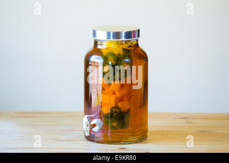 Tequila infused with jalapeno peppers in a tea jar at a restaurant bar. Stock Photo