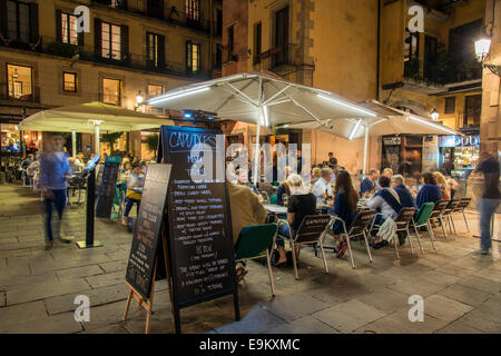 Night view of an outdoor cafe serving tapas with menu blackboard and people seated at tables, Barcelona, Catalonia, Spain Stock Photo