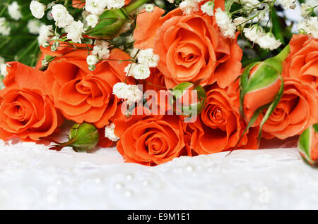 Orange roses on white wedding lace Stock Photo