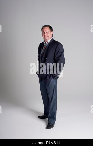 Man in business suit standing with hands in his pockets Stock Photo