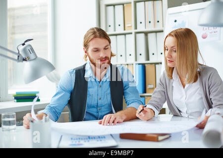 Two Caucasian architects or designers looking at blueprint at meeting Stock Photo