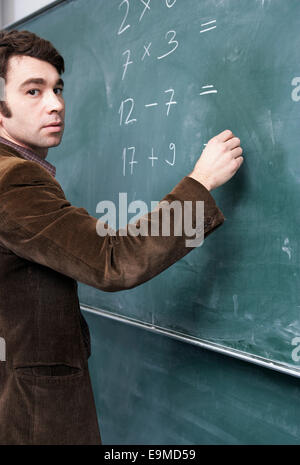 Side view of a man writing on a blackboard Stock Photo