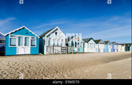 A row of colourful beach huts on a sandy beach Stock Photo