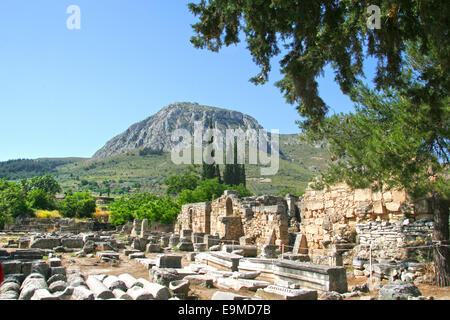 Corinthian columns sit among the ruins at Corinth with a mountain in the background, Peloponnese, Greece. Stock Photo