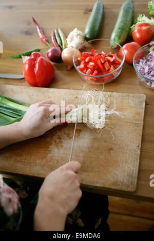 A woman cutting leeks on a cutting board Stock Photo