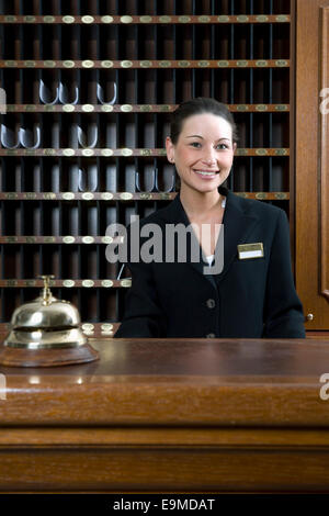 Hotel clerk standing behind desk at hotel reception Stock Photo