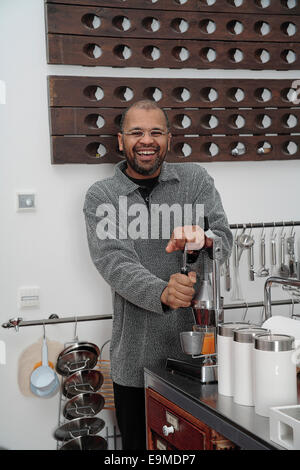 Mature man making fresh orange juice in kitchen Stock Photo