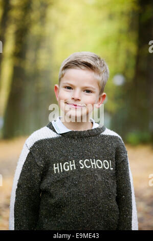 Young boy standing in park in autumn Stock Photo