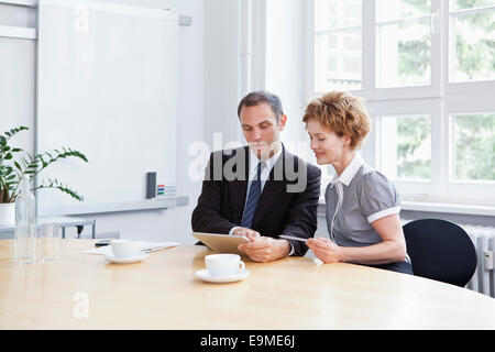 A businessman and businesswoman using a digital tablet in a meeting Stock Photo