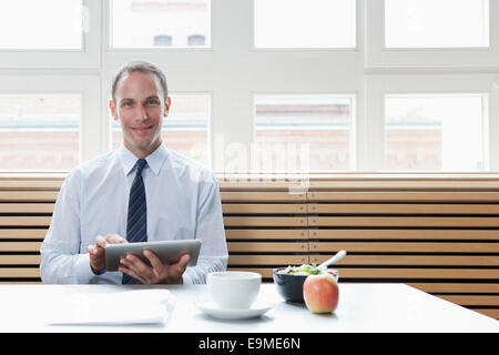 A businessman using a digital tablet on his lunch break Stock Photo