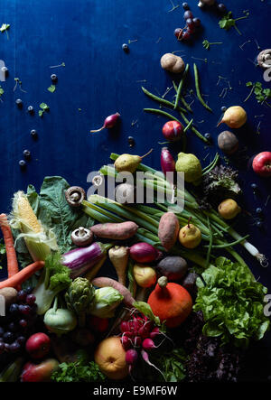 High angle view of fresh vegetables and fruits scattered on blue table Stock Photo