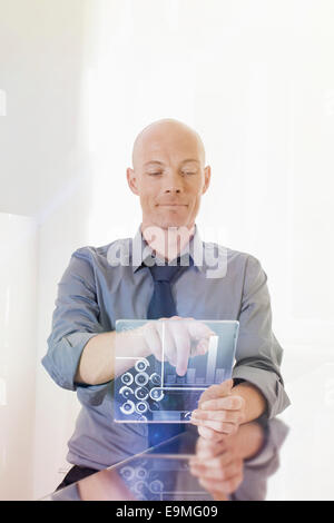 Businessman using futuristic digital tablet at desk in office Stock Photo
