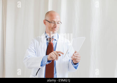 Male doctor touching futuristic digital tablet at clinic Stock Photo
