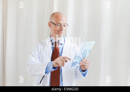 Smiling male doctor touching futuristic digital tablet at clinic Stock Photo