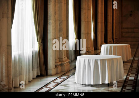 Sunlight falls on two empty round dinner table in a festive marble room Stock Photo