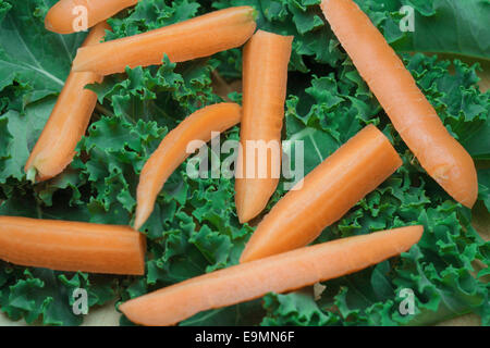 Chopped, uncooked carrots on a bed of curly Kale. Stock Photo