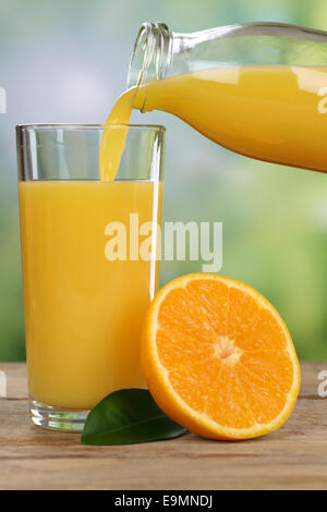 Orange juice pouring from oranges fruits into a glass in summer Stock Photo