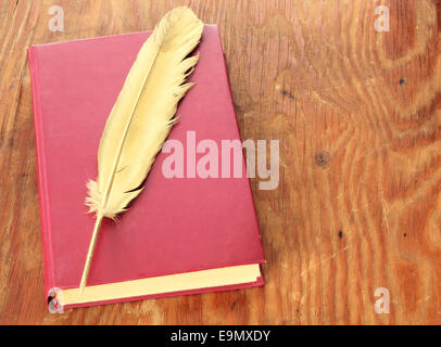 Gold quill pen and red book on grunge wood board Stock Photo