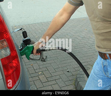 Close-up of a driver filling his car up with petrol or diesel symbolizing non electric cars, the cost of car fuel and transportation Stock Photo