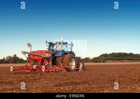 tractor seeding in a field on blue sky background Stock Photo