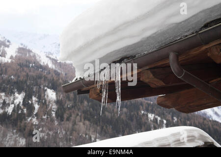 Heavy snow and icicles on a rooftop in Italy. Frozen gutter pipe. Stock Photo