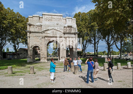 Asian tourists posing in front of the Roman Triumphal Arch of Orange / Arc de triomphe d'Orange, Vaucluse, France Stock Photo