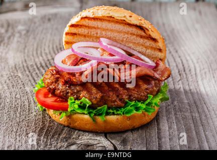 hamburger with bacon and grilled meat on a wooden surface Stock Photo
