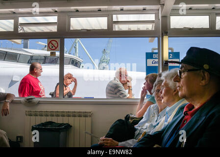 Passengers in the departure lounge at St Peter Port Guernsey watch new arrivals from the cross-channel ferry to England Stock Photo