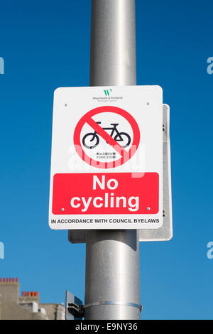 looking up at bright read and white no cycling sign on metal post with blue sky behind Stock Photo