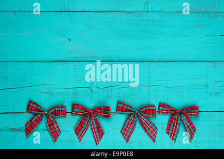 Blank antique teal blue weathered wood background with red plaid Christmas bows border Stock Photo