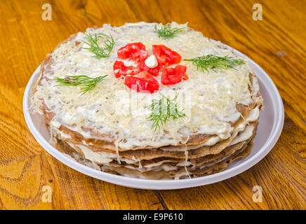 Liver cake with garlic, dill sauce and tomatoes in the white plate on wooden table. Stock Photo