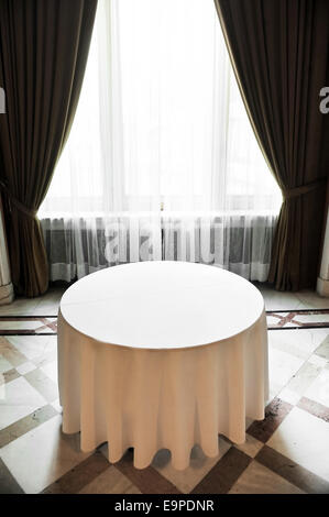 Sunlight falls on an empty round dinner table in a festive marble room Stock Photo