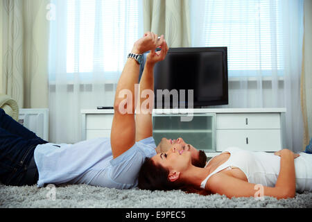 Young couple lying on the floor and using smartphone at home Stock Photo