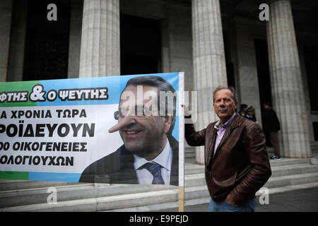 Thessaloniki, Greece. 31st Oct, 2014. An elderly small bondholder holds a banner with a caricature of Greece's Prime Minister Antonis Samaras with the Greek word ''The liar''. On the occasion of World Savings Day about 50 small bondholders who suffered major losses during Greece's massive public debt writeoff on 2012, claim to have been tricked by the government and are demanding compensation. Thessaloniki, greece on October 31, 2014. Credit:  Konstantinos Tsakalidis/Alamy Live News Stock Photo