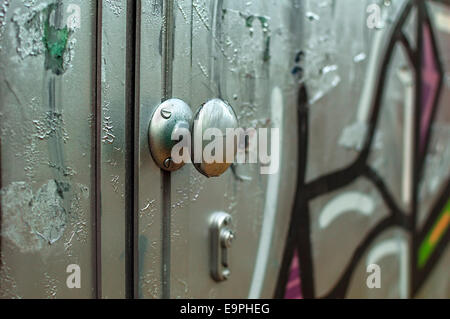 Door covered in graffiti with selective focus on doorknob Stock Photo