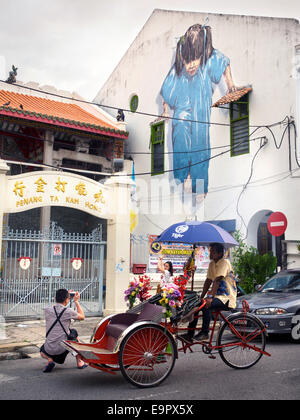 Tourists taking a picture in front of the Little Girl in Blue street art mural in George Town, Penang, Malaysia. Stock Photo