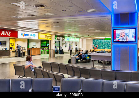 Gatwick airport, UK. A bored cleaner yawning while watching TV on her early morning shift Stock Photo