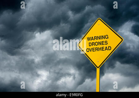Drones Overhead Road Sign: A caution sign in front of storm clouds warning of 'Drones Overhead'. Stock Photo