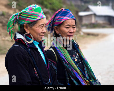 Black Hmong women wearing traditional attire and jewelry standing on the trail to Ta Van village, near Sapa Town, Vietnam. Stock Photo