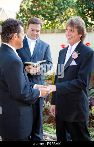 Emotional wedding ceremony of two gay men in a long term committed relationship.  They exchange rings as the minister looks on. Stock Photo