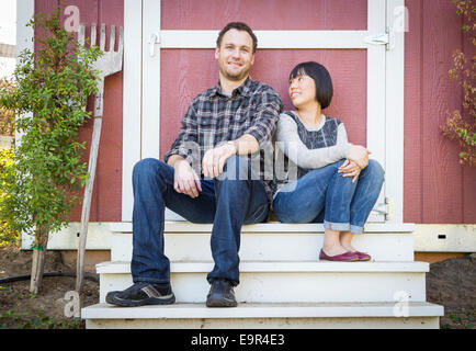 Happy Mixed Race Couple Relaxing on the Steps of Their Barn. Stock Photo